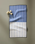 The Harmony Haze fitness towel by Happy Hemera, made from recycled materials, features a blue and white checkered design and two white chess pawns near the top left corner on a gray surface.