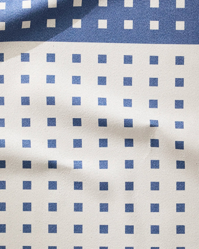 The Harmony Haze fitness towel by Happy Hemera features an ultra-absorbent fabric with evenly spaced blue squares on a white background, accented by gentle waves and folds from visible light and shadow.