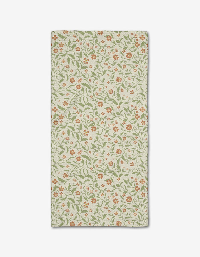 The Hawthorns Bar Towel by Danelys Sidron is rectangular, beige, and made from recycled materials, showcasing an all-over floral design with small orange flowers and green leafy vines, shown flat on a white background.