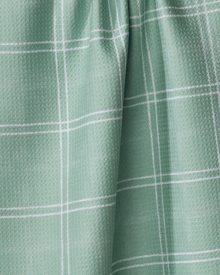 The Geometry Hearth Meadow dish towel features a light green absorbent fabric with a subtle textured pattern and thin white grid lines, displayed with a slightly gathered drape.