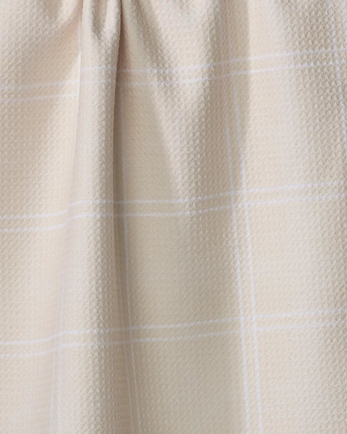 Close-up of the Geometry Hearth Oat tea towel, featuring a beige textured fabric with a subtle white plaid pattern and a gathered seam at the top.