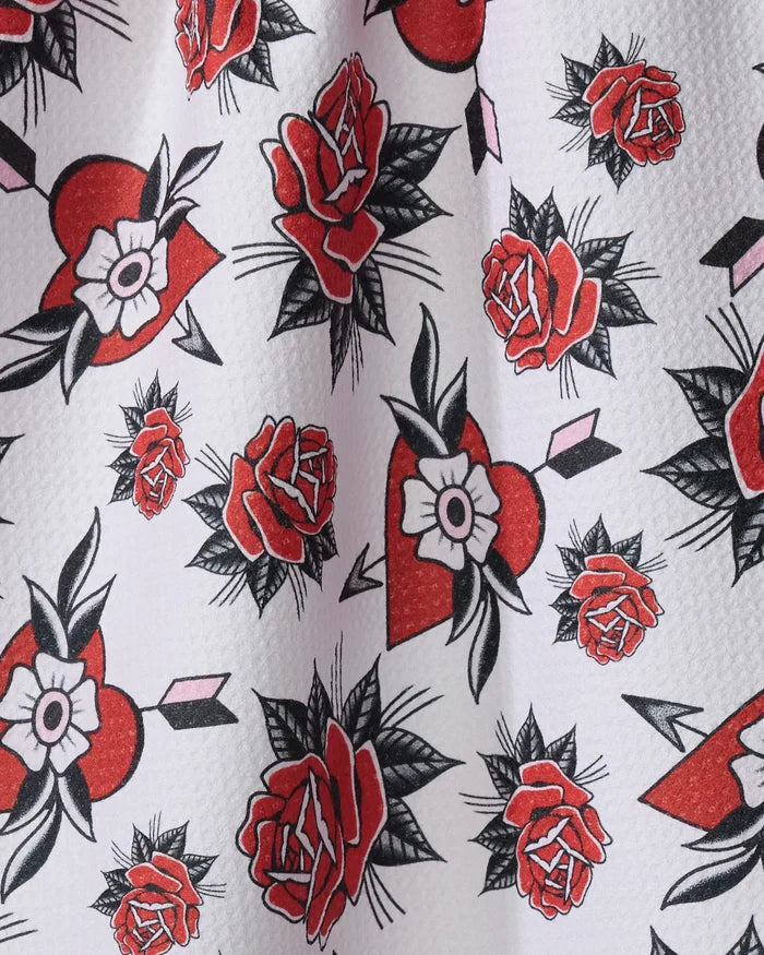 Hearts and Roses by Cole Strem features tattoo-inspired red roses, hearts with white flowers, and pink arrows on a light textured background—repeating across this recycled kitchen towel for style and sustainability.