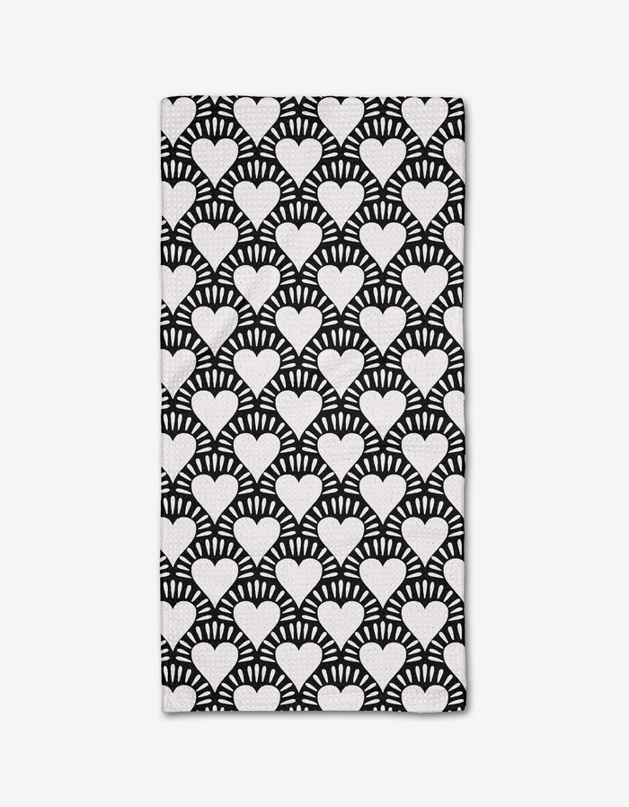 The Heartthrob Onyx bar towel by Charlie Rowan Designs is made from Geoweave fabric and showcases bold, high-contrast white hearts with radiating lines on a black background for a striking geometric look.