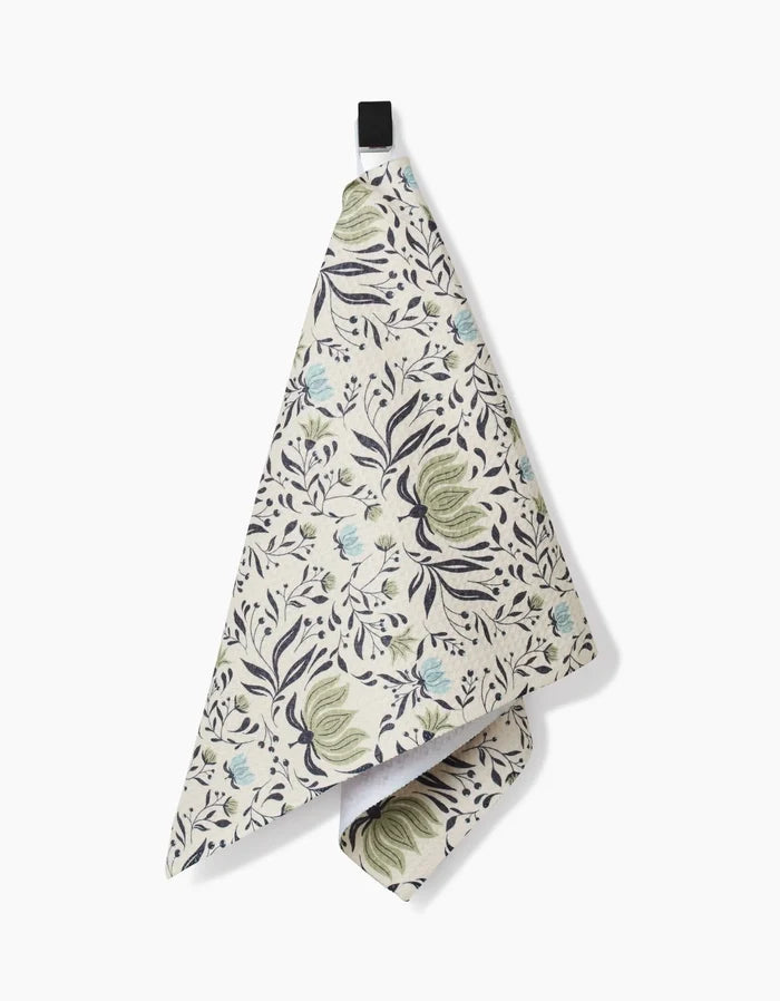 The Hello Flowers hanging kitchen bar towel by Amita Nair features a floral pattern in green, blue, and black on white. Made from ultra-absorbent Geoweave fabric, it’s pictured against a plain white background.