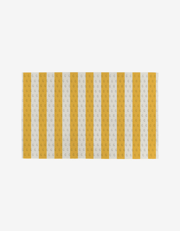 Here Comes The Sun by Aubrey Fairchild is a reusable rectangular mat with white background, alternating yellow and light gray vertical stripes, each with repeating G motifs—an eco-friendly alternative to Not Paper Towels.
