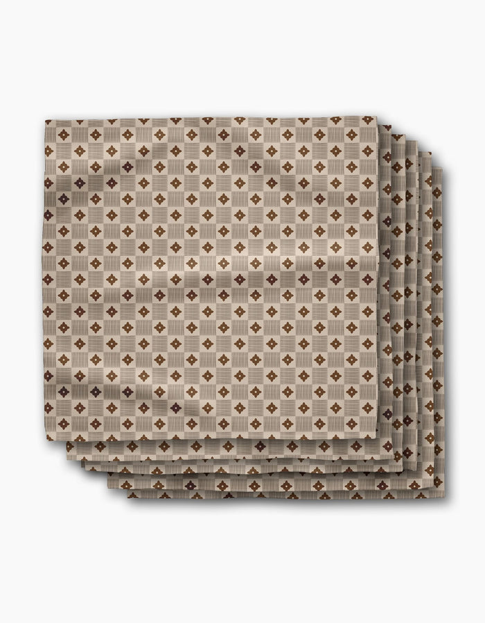 Four absorbent dinner napkins from Geometry’s Heritage Stamp collection feature a geometric brown and beige diamond pattern, neatly folded and displayed on a white background—perfect for adding style to your table.