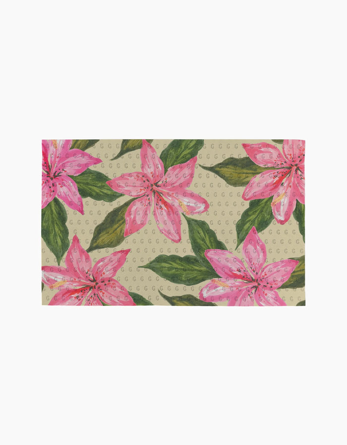 The Hibiscus Haze by Geometry features a beige background with large pink lilies, green leaves, and repeating circular patterns—crafted from post-consumer recycled materials.