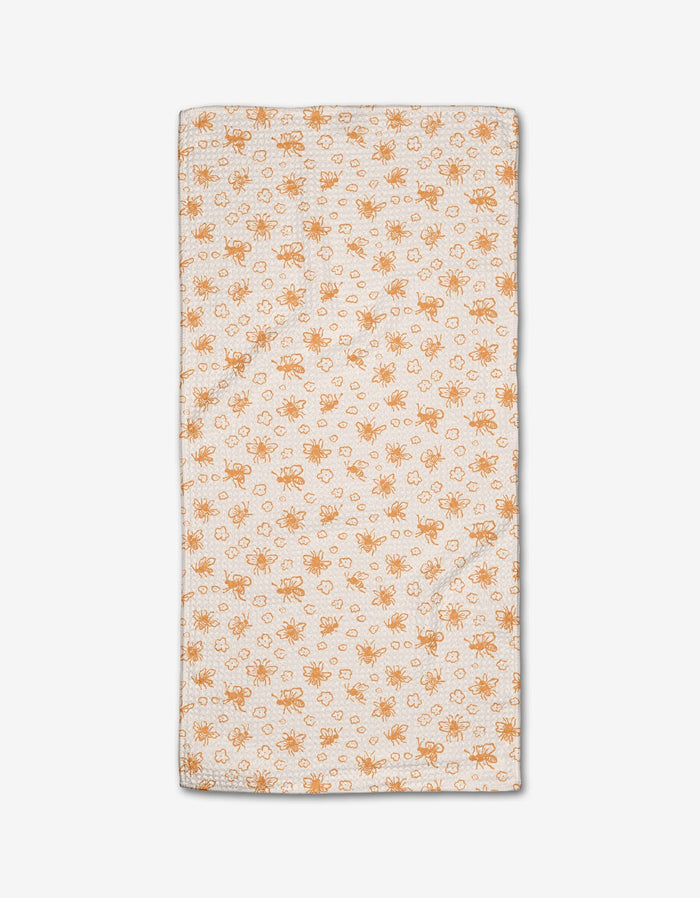 The Honey Bee Bar Towel by Kayla Ann is rectangular and white, featuring an orange floral and leaf pattern with neatly stitched edges, displayed flat on a white background.
