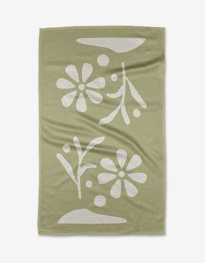 The Honey Dew tea towel by Graphics and Grain features a sage green, textured surface with a white floral and leaf pattern, abstract shapes, and dots. Made from quick-drying recycled materials.