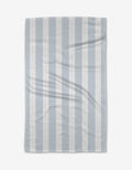 The BetterDays Hormones Tea Towel, featuring light blue and white vertical stripes with a waffle texture, is laid flat on a white background. Made from Geoweave™ fabric, it displays a slight wrinkle for added texture.