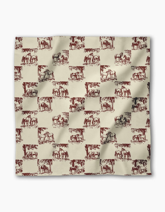 The Geometry Horse Check Cream fabric square features a repeating pattern of vintage-style horses in red and dark gray on a beige checkered background, adding charm to any reusable dinner napkin set.