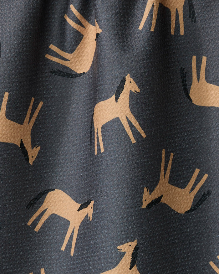 The Coit Creative "Horses" tea towel showcases stylized tan horses in running and jumping poses on a dark background, crafted from recycled materials.