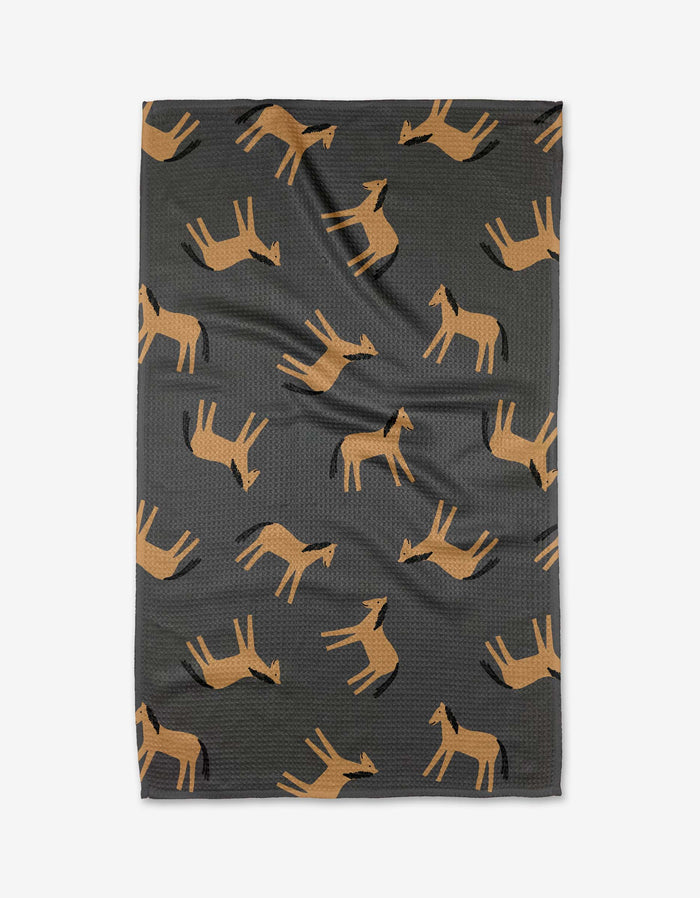 The Coit Creative Horses blanket is dark gray, made from recycled materials, and showcases a repeating pattern of stylized brown horses in various directions.