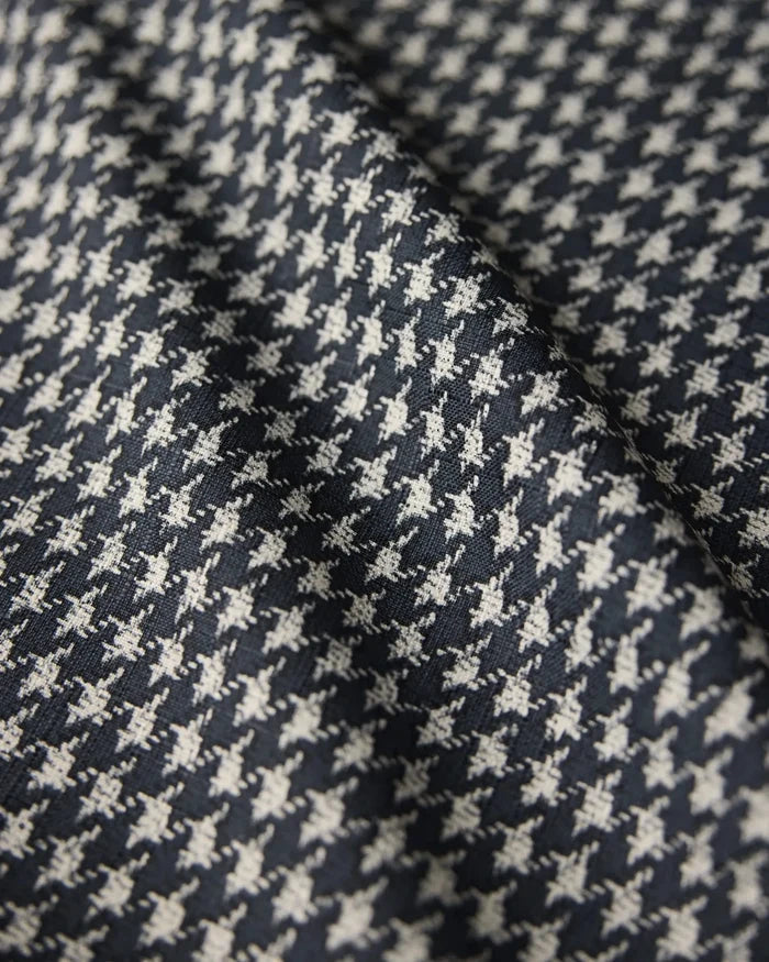 Close-up of the Houndstooth Black tablecloth by Geometry, featuring a classic black and white houndstooth pattern on lightweight woven fabric with a central fold.