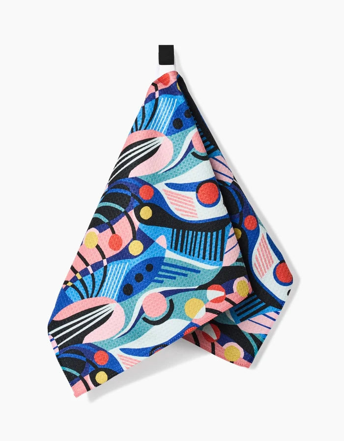The Imagined Realm Bar Towel by Masha Volnova features a vibrant abstract geometric design in blue, pink, red, yellow, and black. Crafted from ultra-absorbent Geoweave fabric for style and practicality, it hangs by a black loop against a white background.
