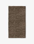The Imprint rug by Studio Jeannot is a rectangular brown rug featuring an abstract, textured pattern of swirling lines on a white background, crafted with ultra-absorbent Geoweave technology for enhanced comfort.
