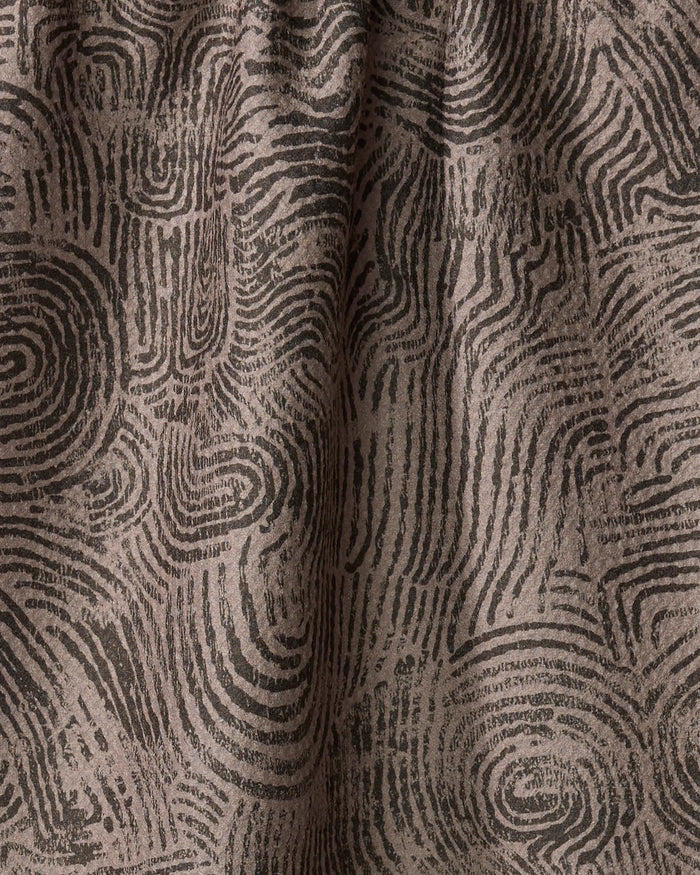 Close-up of Studio Jeannot’s Imprint recycled kitchen towel, featuring a textured pattern of overlapping black fingerprint-like swirls on a brown background with organic curves and subtle folds.