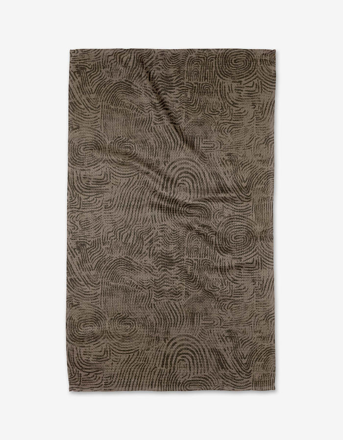 Imprint by Studio Jeannot is a rectangular brown tea towel featuring an abstract, swirling pattern like fingerprints or topographic lines. Made from recycled materials, it’s stylish, eco-friendly, and shown flat on a white background.