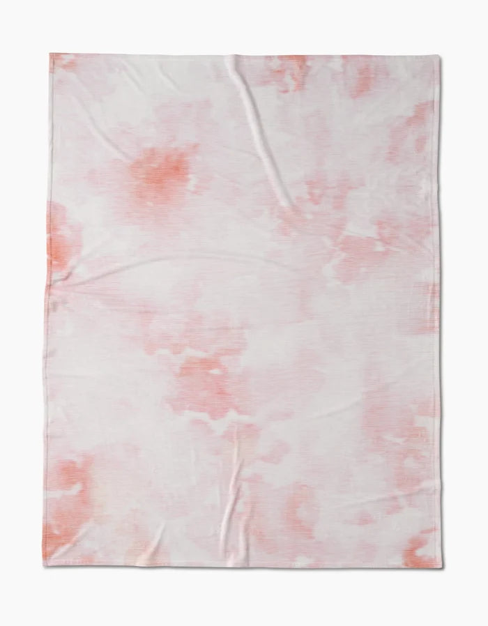 Geometry’s In the Clouds features a soft, lightweight fabric with silky texture and a subtle pink and orange tie-dye pattern, shown laid flat with slight wrinkles.
