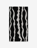 The GEOMETRY Ink Twist bath towel is made from recycled materials and features a black background with wavy, vertical white stripes of varying thickness for a stylish, ultra-absorbent finish.