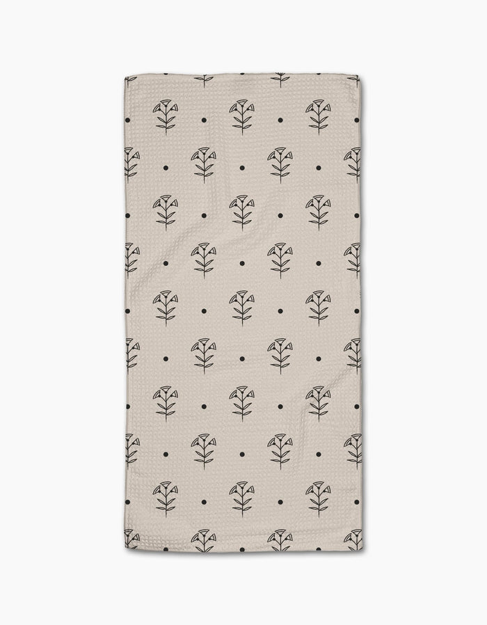 The Cole Strem Inked Bloom Bar Towel is beige and rectangular, featuring a grid of black line-drawn flowers and dots. Crafted from Geoweave fabric, it offers exceptional durability and absorbency.