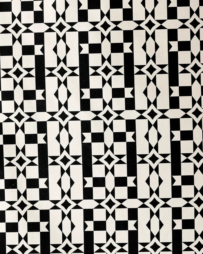 The Intermission yoga towel by Geometry features a black and white geometric pattern of interlocking squares, diamonds, and triangles for a symmetrical optical illusion on recycled material.