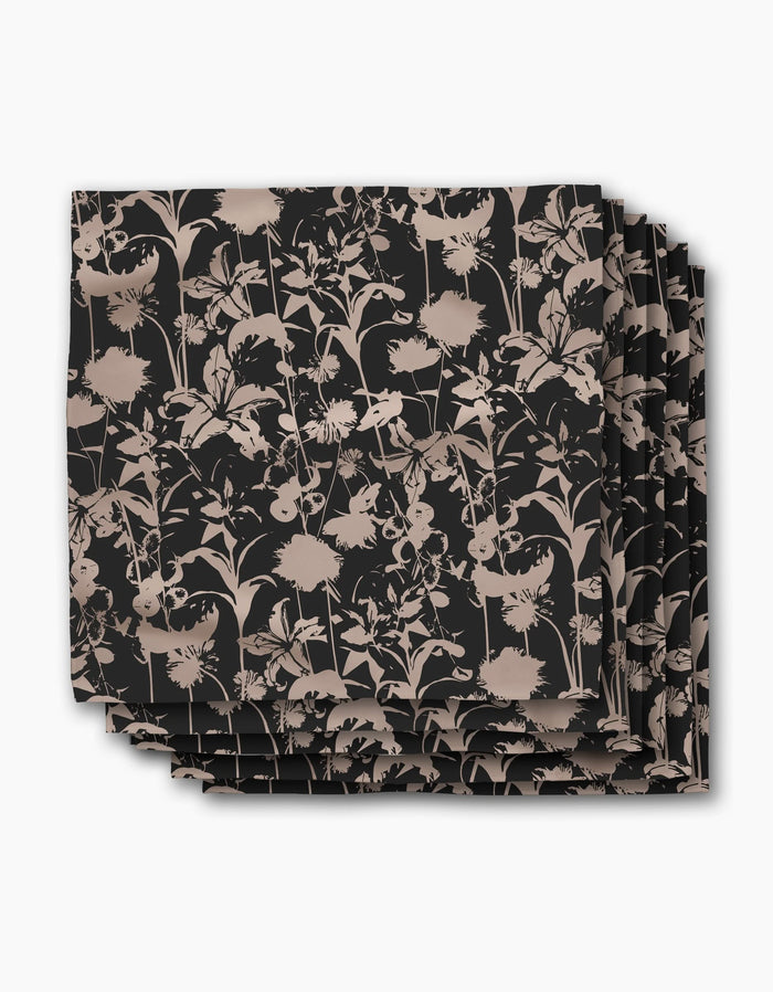 A set of four square recycled dinner napkins by Geometry, named Inverted Floral Black, featuring a beige floral pattern with assorted flowers and leaves on a black background.