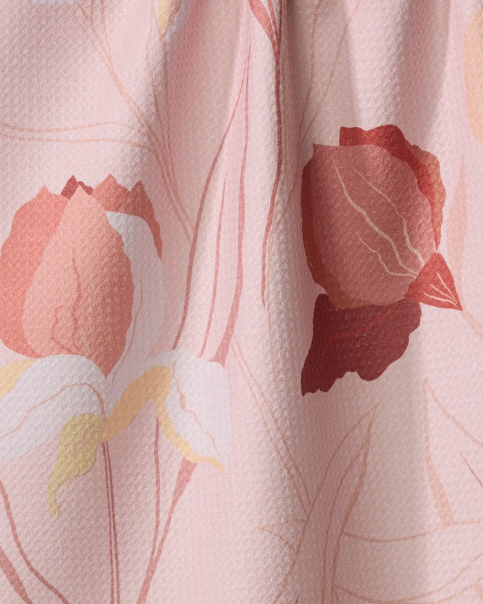 Close-up of the Elana Gabrielle "Iris" dish towel, showing its absorbent, textured surface with a floral pattern in pink, red, and white abstract flowers and leaves on a light pink background.