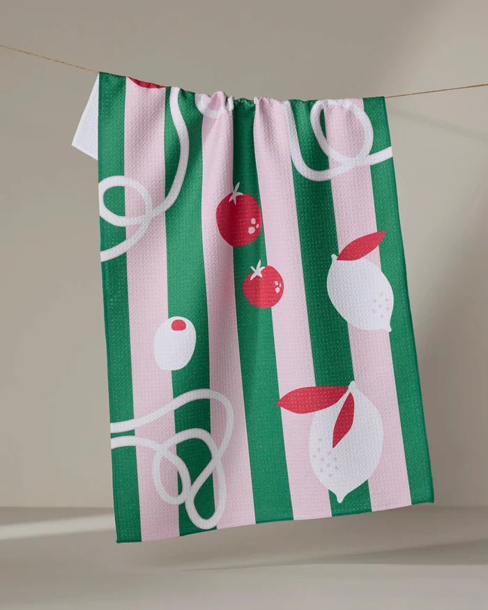 The Italian Mood tea towel by Marina Solodka hangs on a line, ultra-absorbent with green and pink stripes. It features charming illustrations of tomatoes, garlic bulbs, and white squiggly noodle-like lines.