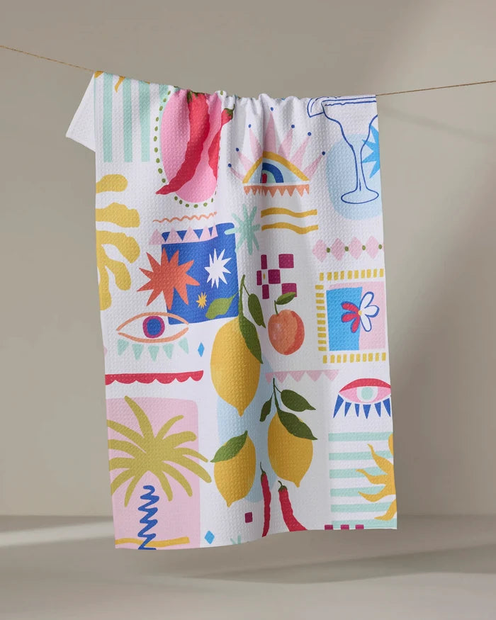 The "Italian Picnic" dish towel by Marina Solodka features bold, abstract designs—lemons, chili peppers, eyes, a cocktail glass, and palm trees—on absorbent fabric. Ideal as an eco-friendly kitchen towel for daily use.