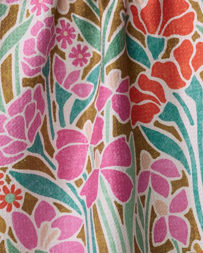 A close-up of the Janae kitchen towel by Amy MacCready, showcasing a textured, recycled fabric with a gathered floral print—pink, red, and orange flowers with green leaves and olive accents on white.