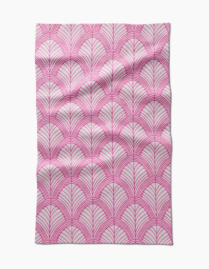 The Amy MacCready Jaskin tea towel is rectangular, made from Geoweave fabric, and features a pink geometric pattern of overlapping semi-circles and radiating lines on a white background, with subtle creases and folds.
