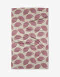 The Jasmine rug by Becki Owens is a rectangular beige piece featuring a repeating pattern of pink fan-shaped leaves, crafted from recycled materials. It appears slightly wrinkled and is displayed on a white background.