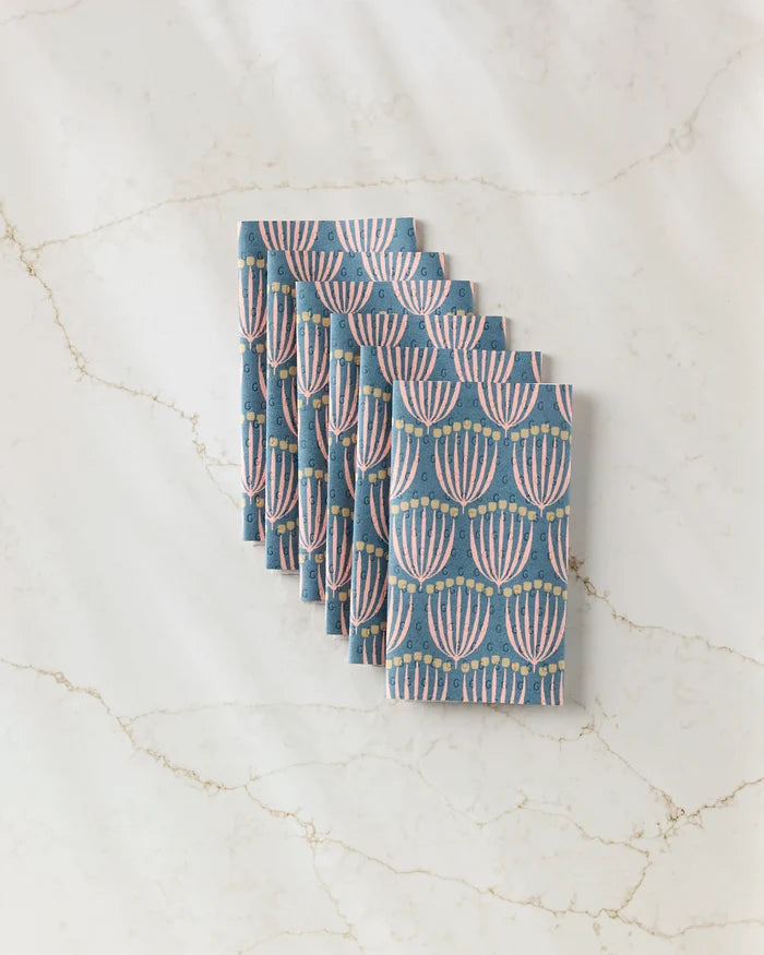 A stack of Josie blue reusable paper towels by Amy MacCready, featuring a pink and gold menorah pattern, neatly arranged on a white marble surface.