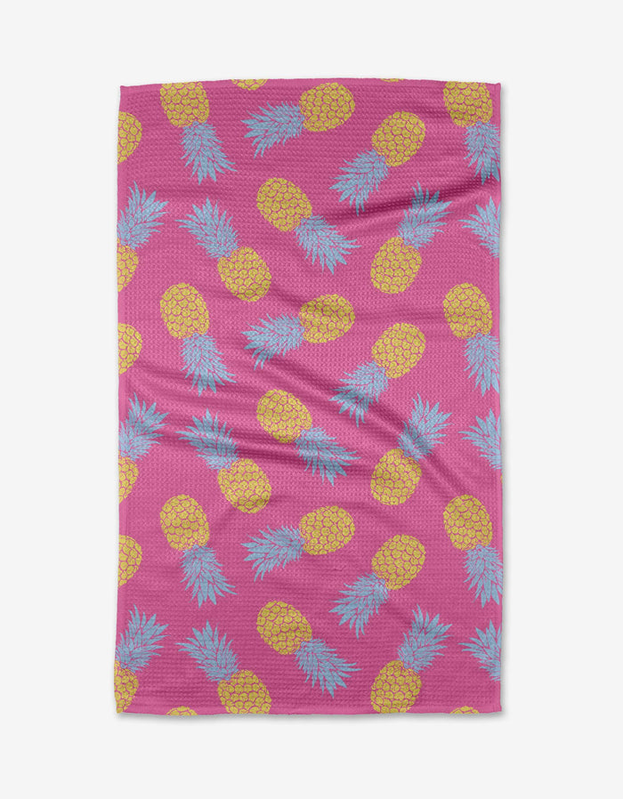 The Juicy Pineapples towel by Ashley Celena features a pink backdrop with yellow pineapples and blue-green leaves, made from ultra-absorbent Geoweave fabric for superior drying.