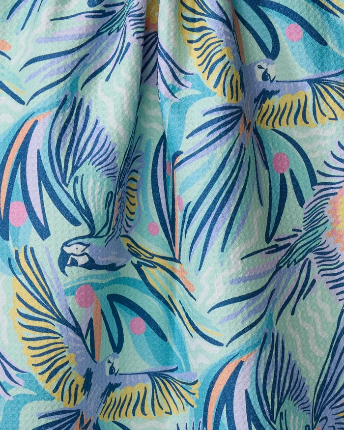 The Jungle Birds tea towel by Masha Volnova features illustrated parrots in flight among abstract blue, yellow, pink, and green tropical leaves. Its slightly textured fabric drapes beautifully for a unique kitchen accent.