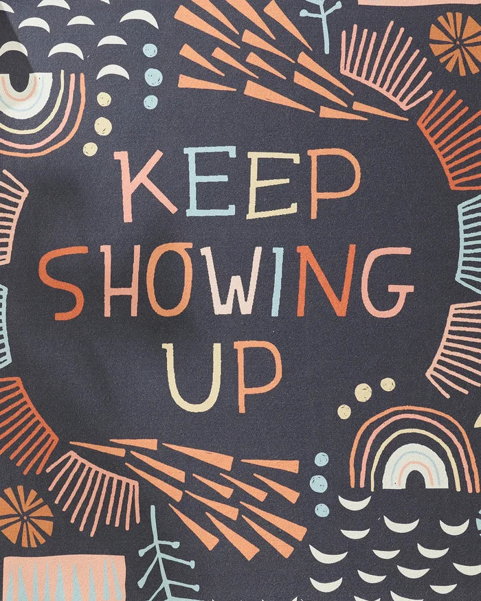 Colorful, abstract shapes in orange, yellow, blue, and off-white surround the hand-lettered "Keep Showing Up" by Jessica Swift—an inspiring choice for your next session with this non-slip yoga towel.