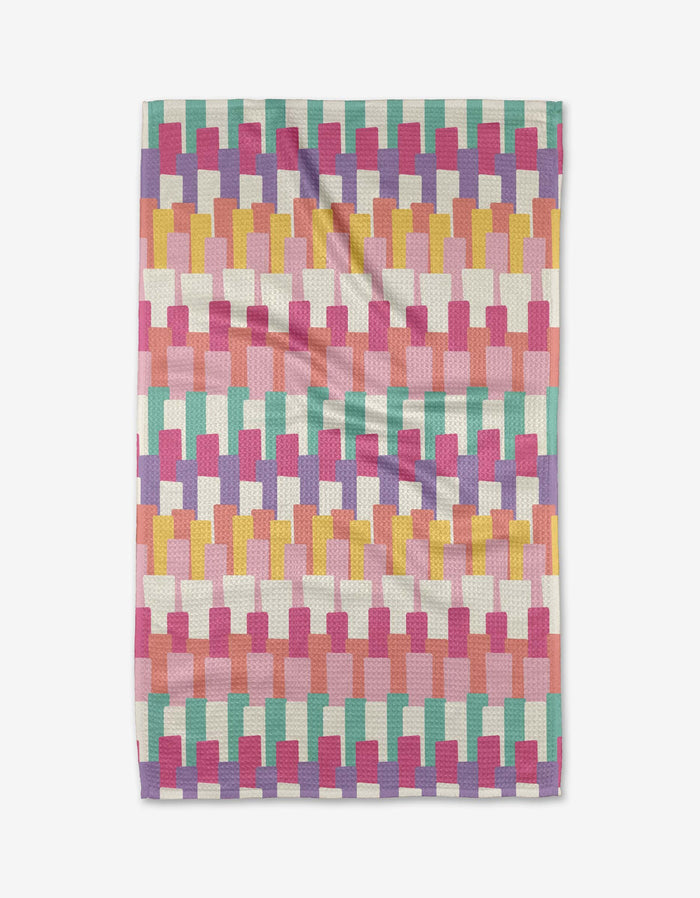 The Keys tea towel by Rebecca Bobko features a geometric, brick-like pattern in pink, mustard yellow, turquoise, coral, and white Geoweave fabric, shown flat against a white background.