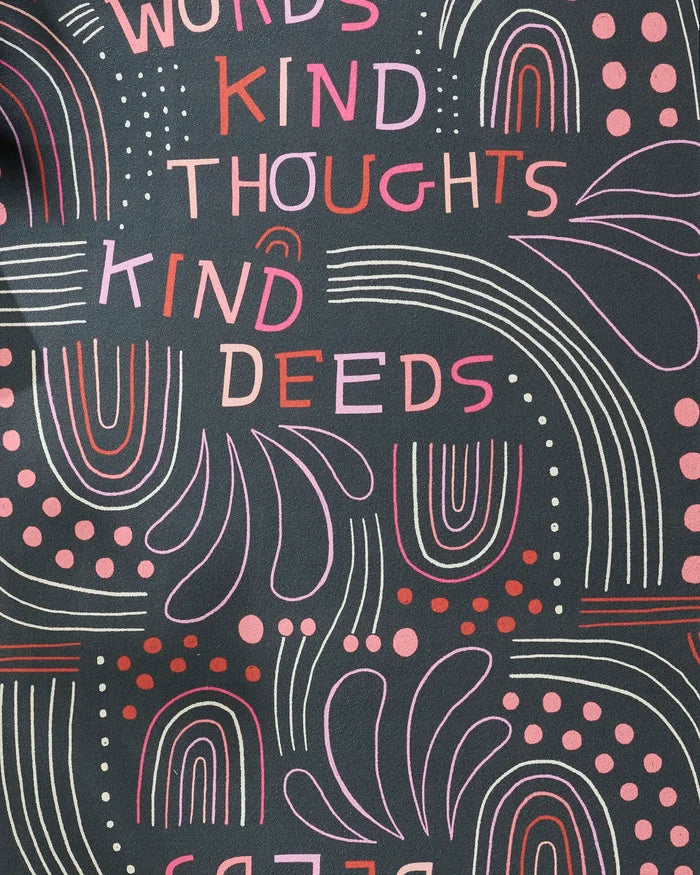 The Jessica Swift "Kind Hearts" yoga towel features a non-slip recycled design with abstract shapes, rainbows, dots, and lines in pink and red on black. “KIND WORDS, KIND THOUGHTS, KIND DEEDS” appears in playful colors across the towel.