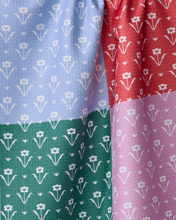 The Buy Guide’s Ladylake - Patchwork is a colorful recycled tea towel divided into light blue, red, green, and pink sections with a repeating white floral pattern—perfect as an absorbent dish towel for your kitchen.