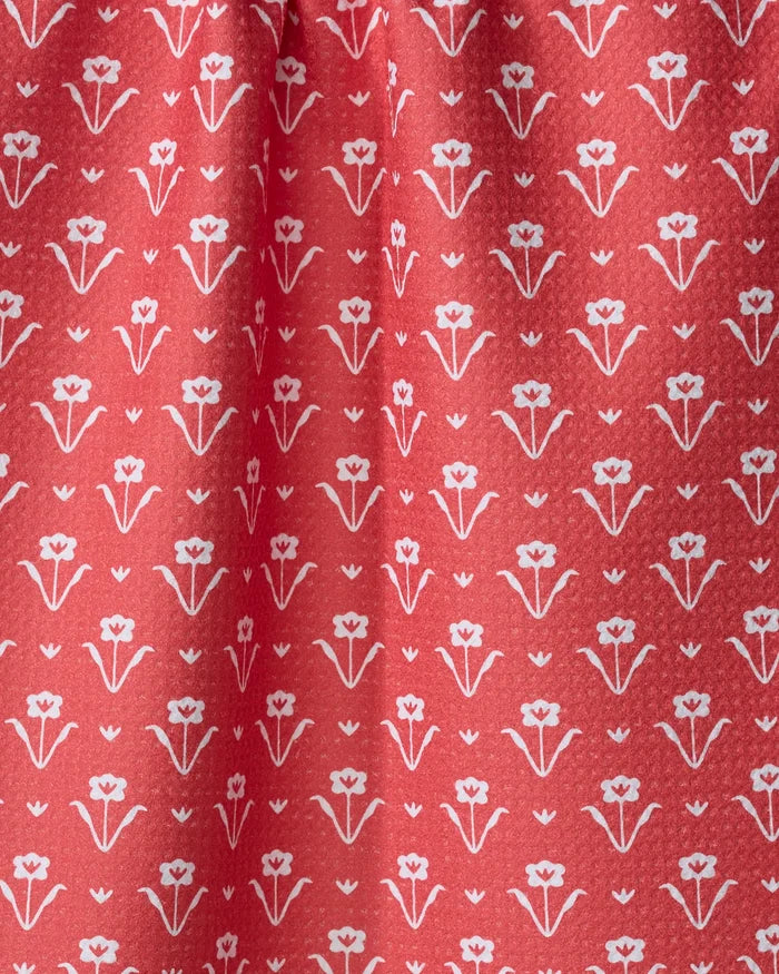 Close-up of the Ladylake - Red tea towel by The Buy Guide. Ultra-absorbent red fabric features a white floral pattern, with gentle folds and soft shadows near the gathered top.