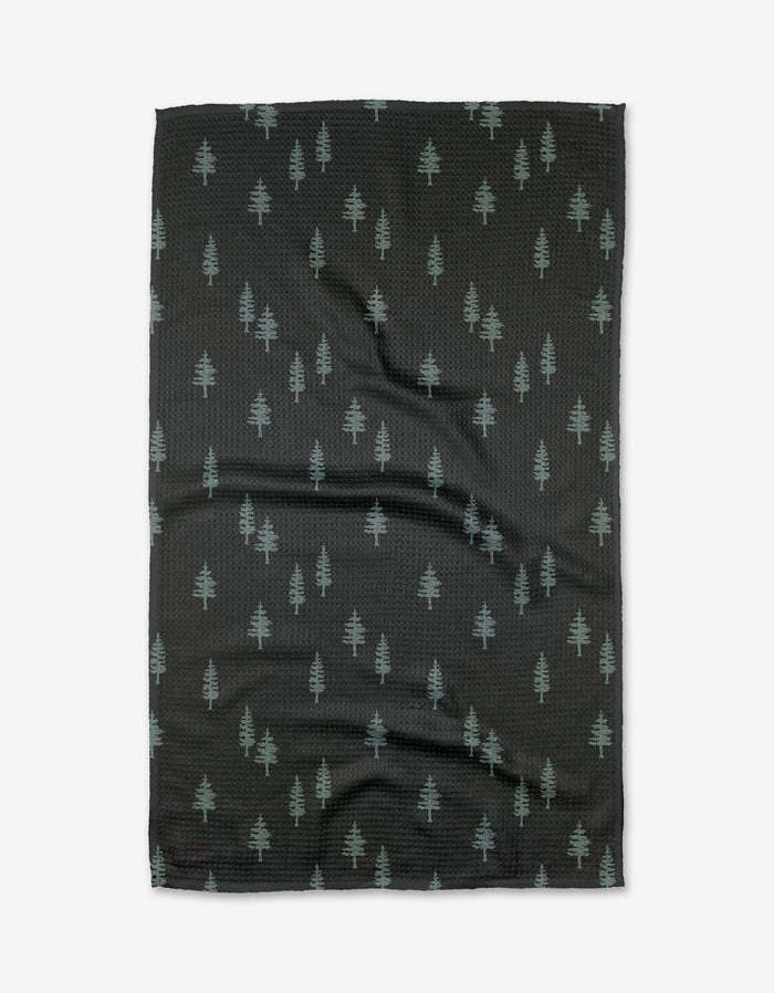The Lake Pine tea towel by Coit Creative is made of black Geoweave fabric with a pattern of small, light green pine trees evenly distributed across the surface.
