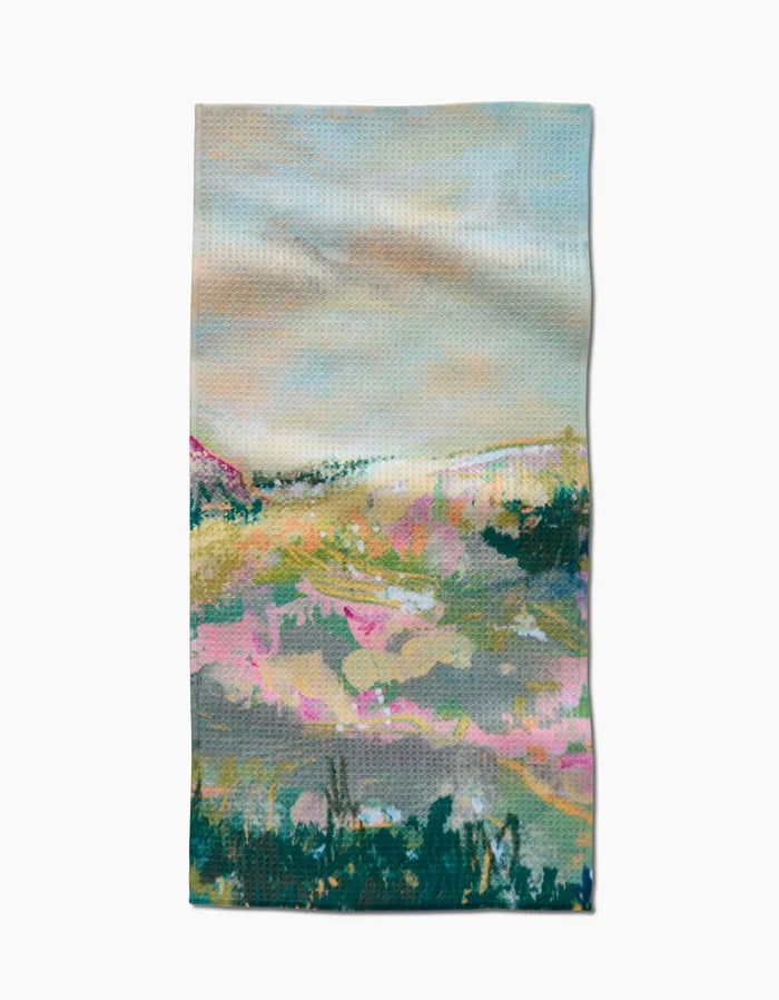 The Land of Milk and Honey Bar Towel by Taryn Brennan features an abstract landscape in soft pastel pinks, greens, and blues with hills and clouds. Made from Geoweave fabric for superior absorbency and durability.