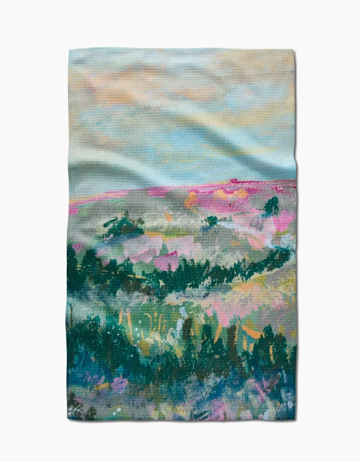 The Land of Milk and Honey Kitchen Tea Towel by Taryn Brennan features a dreamy, impressionist-style landscape in soft blue, pink, green, and purple on Geoweave fabric for a textured, abstract effect.