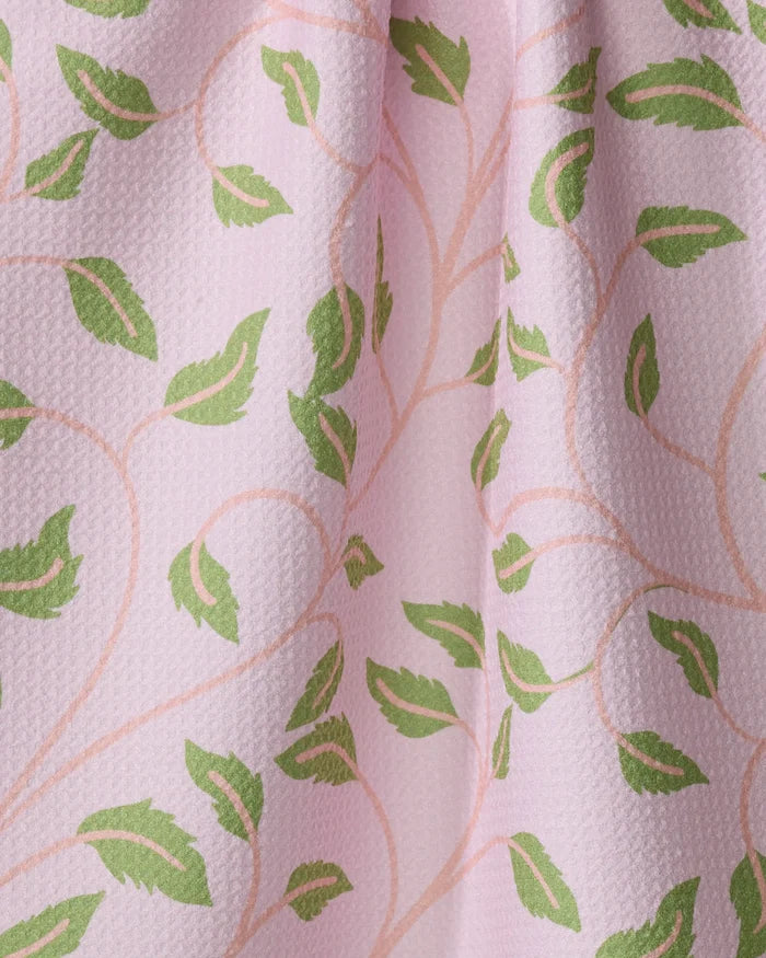 Close-up of the Leafy Maze tea towel by Jasmine Blooms Designs, featuring a textured pink surface with green leafy and subtle beige vine patterns, crafted from recycled materials for a soft, decorative touch.