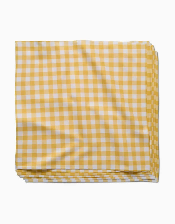 The GEOMETRY Lemon Gingham napkin, crafted from Geosuede fabric in a yellow and white checkered pattern, is neatly folded on a white background.