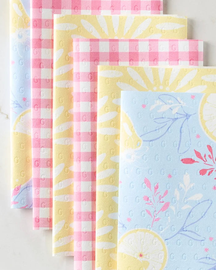 Four folded Lemon Pop reusable paper towels by Ashley Celena are arranged side by side—two in pink and white gingham, two with blue, yellow, and white designs featuring lemons, sunbursts, and botanical accents.