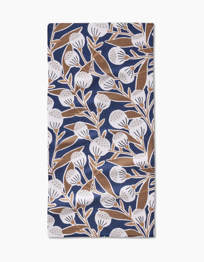 The Leslie napkin by Amy MacCready features ultra-absorbent Geoweave fabric with a blue background and a brown-and-white botanical design of leaves and round flowers.