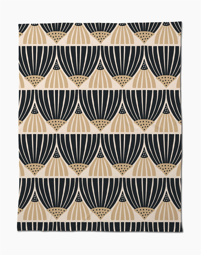 The Letitia Dark Butter Blanket by Amy MacCready features black and tan geometric fan patterns on white, arranged in horizontal rows. Made from eco-friendly recycled materials, it offers a modern, minimalist style.