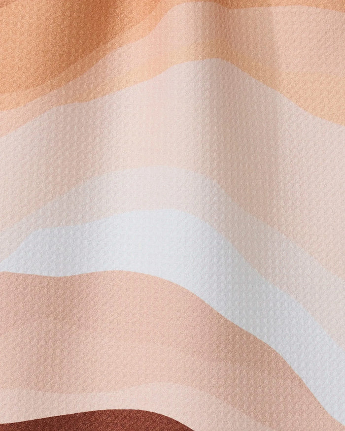 Levels of Fall by GEOMETRY features wavy, horizontal layers in beige, peach, tan, and brown tones—evoking a stylized landscape. This design is the inspiration for an ultra-absorbent towel made from recycled materials.